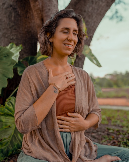 Bénédicte Donet meditating under a tree, hand on her heart